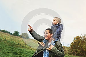 Pointing, father and child on shoulder in nature with happy smile, grass and bonding in outdoor garden. Man, son and