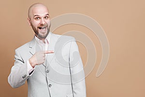 Pointing finger and happy portrait of handsome middle aged businessman in classic light gray suit standing, looking