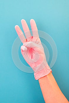 Pointing finger at number three, in pink gloves, on blue backdrop of