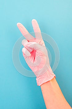 Pointing finger at number two, in pink gloves, on blue backdrop