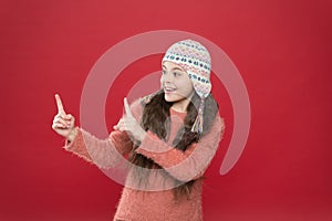 Pointing like this. Winter outfit. Cute model enjoy winter style. Small child long hair wear hat red background