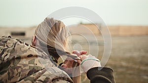 Poise in Conflict: Soldier Braiding Hair Amidst the Harshness of War