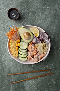 Poke bowl with salmon and avocado, quinoa, fresh cucumber, red onion, carrot and pumpkin, lemon, sesame and soy sauce for spice an