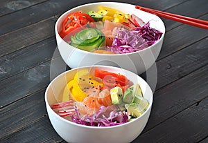 Poke bowls with fresh salmon, crystal noodles, radish, avocado, sweet pepper, cucumber, sesame seeds, red cabbage.