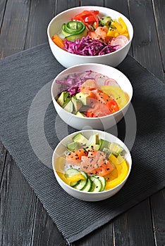 Poke bowls with fresh salmon, crystal noodles, radish, avocado, sweet pepper, cucumber, sesame seeds, red cabbage