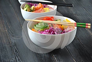 Poke bowls with fresh salmon, crystal noodles, radish, avocado, sweet pepper, cucumber, sesame seeds, red cabbage.