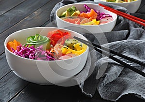 Poke bowls with fresh salmon, crystal noodles, radish, avocado, sweet pepper, cucumber, sesame seeds, red cabbage