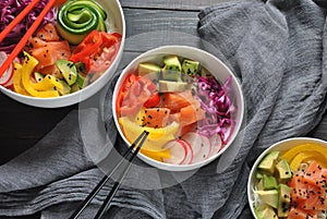 Poke bowls with fresh salmon, crystal noodles, radish, avocado, sweet pepper, cucumber, sesame seeds, red cabbage.