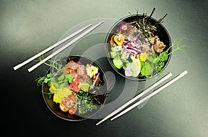 Poke salads with tuna and beef in bowls on the table. Two bowls of poke salad with chopsticks on a gray background