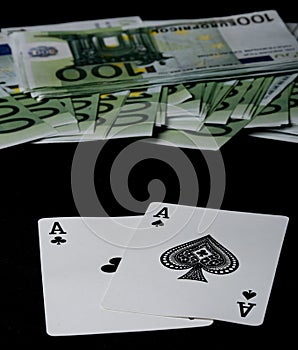 Poker cards: 2 black aces on a black background with many 100 euro banknotes