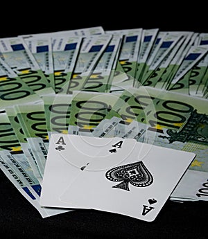 Poker cards: two black aces on a black background with many 100 euro banknotes