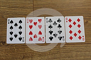 Poker cards on a wooden backround, set of tens of clubs, diamonds, spades, and hearts