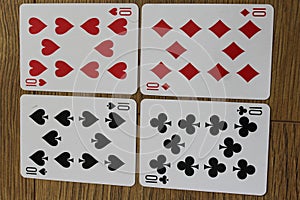 Poker cards on a wooden backround, set of tens of clubs, diamonds, spades, and hearts