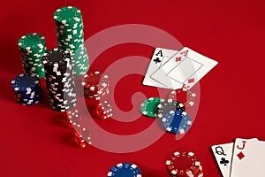 Poker chips and aces on red background. Group of different poker chips. Casino background.