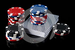 Poker chips on a deck of cards for playing poker on a black background with reflection