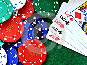 Poker chips & full house cards on green felt table