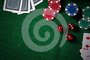 Poker chips and gamble cards on casino green table with low key