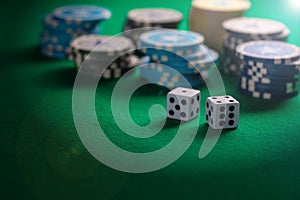 Poker chips piles and dice on green felt background, copy space