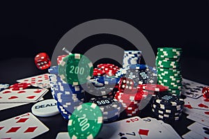 Poker chips, playing cards and dices isolated over black casino table background. Gambling tournament earnings, betting for