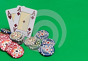 Poker chips stack and playing cards on green table.