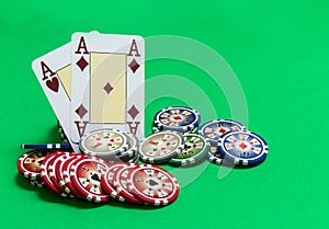 Poker chips stack and playing cards on green table