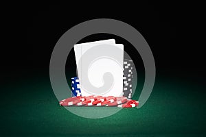 Poker chips on table with pair of blank cards