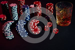 Poker chips and wine glass of cognac on dark table. Gambling