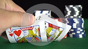 Poker game with a pair of jacks betting all the poker chips. Close-up of a gambler hand is holding playing cards in