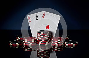 Poker game with three of kind or set combination. Chips and cards on black table. Successful and win three aces