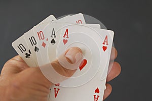 Poker hand full house with three cards of ten and two aces - close up on black background