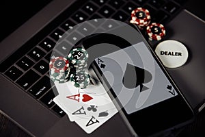 Poker play online concept. Poker chips, playing cards and smartphone on keyboard of laptop