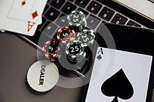 Poker play online. Poker chips, playing cards and smartphone on keyboard