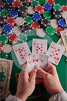 A poker player in a casino, a combination of straight flush cards, a lot of money and chips. Vertical frame