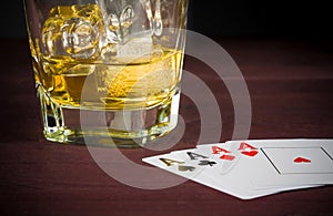 Poker playing cards near wiskey glass