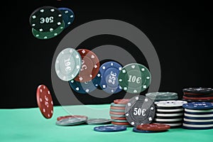 Poker playing chips on a green table and black background. Online gambling. Addiction. Falling poker chips