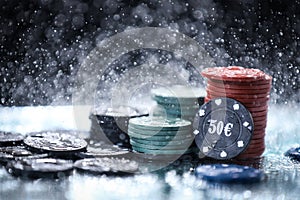 Poker playing chips on a green table and black background under the water drops. Online gambling.