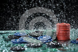 Poker playing chips on a green table and black background under the water drops. Online gambling.