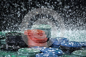 Poker playing chips on a green table and black background under the water drops. Online gambling.