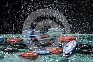 Poker playing chips on a green table and black background under the water drops. Online gambling. Addiction. Casino.