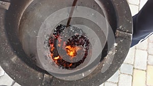 a poker smashes a smoldering coal at the bottom of the tandoor