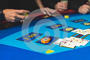 Poker table view with a pack of cards, tokens, alcohol drinks, dollar money and group of gambling rich wealthy people playing