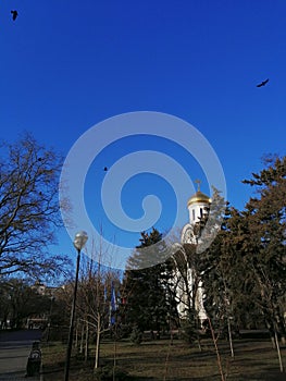 Pokrovsky temple with crows hovering above it on a clear autumn day. South of Russia, Rostov-on-don