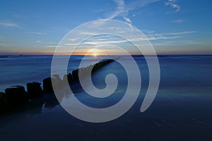 Poland, Baltic. Sunset over the sea. Breakwater on the smooth surface of the sea.