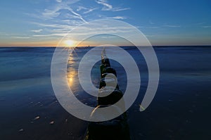 Poland, Baltic. Sunset over the sea. Breakwater on the smooth surface of the sea.