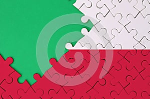 Poland flag is depicted on a completed jigsaw puzzle with free green copy space on the left side