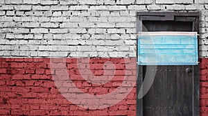 Poland flag painted on brick wall and closed door with medical mask protected