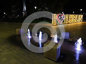 Poland, Lublin. Illuminated fountain at night and inscription Lublin on Litewski Square at night.