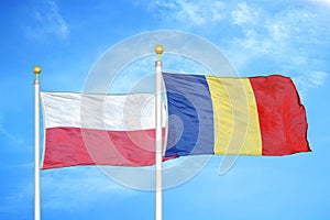 Poland and Romania two flags on flagpoles and blue cloudy sky