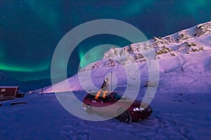 The polar arctic man Northern lights aurora borealis sky star in Norway Svalbard in Longyearbyen city moon mountains