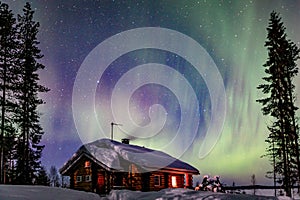 Polar arctic Northern lights Aurora Borealis activity over wooden cottage in winter Finland, Lapland